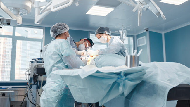 A group of doctors and assistants around an operating table in an operating room.