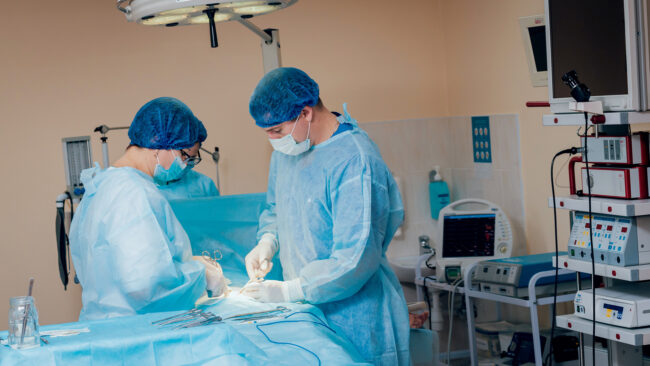 A pair of doctors operating on a patient in the operating room.